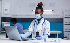 African american woman with doctor job holding bottle of medicine